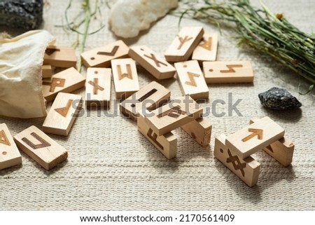 ON THE NATURAL LINEN FABRIC THERE ARE TRADITIONAL WOODEN RUNES LIKE DOMINOES WITH DIVINATION SYMBOLS WITH HEALING MAGICAL DRY HERBS FOLDED SAMPLING FROM RANDOM 