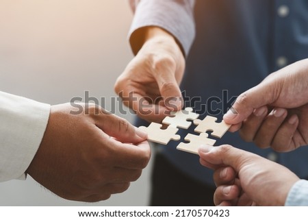 business people team holds in hand a jigsaw or puzzle pieces  in the office for concept of troubleshooting, teamwork, Unity and partnership. success and strategy concept. Royalty-Free Stock Photo #2170570423