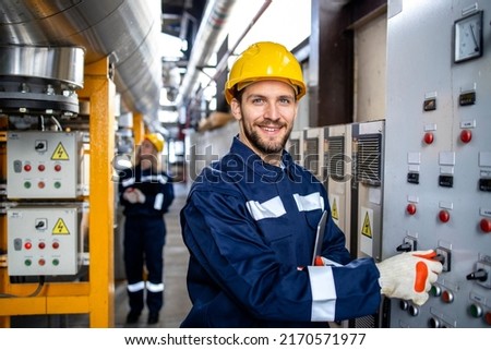 Portrait of an industrial electric engineer standing by power supply inside oil refinery. Royalty-Free Stock Photo #2170571977