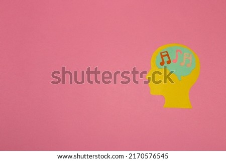 yellow head with a brain with notes, listening to music, pink background with copy space, creative modern design