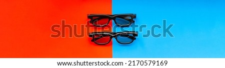3D glasses for watching movies in the cinema and at home on a red-blue background close-up, two pairs of black 3D glasses banner. Cinema banner with place for text