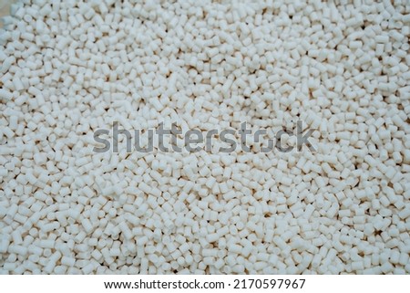Granules of polymer plastic of white color, petrochemical production of plastics, a bunch of crystalline debris, round tubes are cut finely. High quality photo