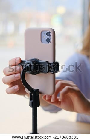 Close-up of a phone on a tripod filming a girl blogging Royalty-Free Stock Photo #2170608381