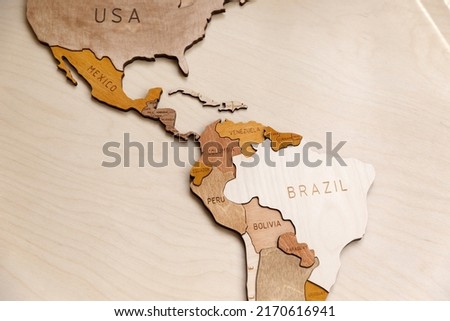 Wooden map of the world on a light background. Self made. Plywood. In beige tones. Central and South America. Geography of Latin America. Mexico, Brazil, Cuba, Venezuela, Bolivia.
