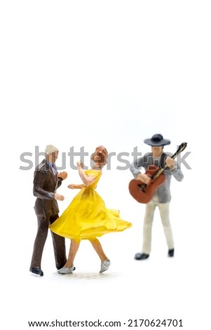 Miniature people Couple dancing with a guitarist playing the guitar on white background Royalty-Free Stock Photo #2170624701