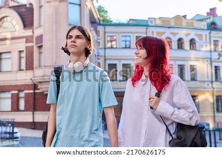 Couple of happy teenage friends walking holding hands, outdoor