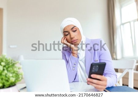 Sad young muslim woman using mobile phone and laptop