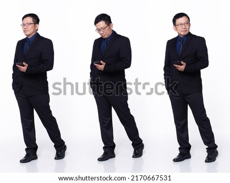 Full length 60s 50s Asian Senior man business executive manager, walking forward left right, wear black formal suit. Confident Office male carry internet phone over white background isolated