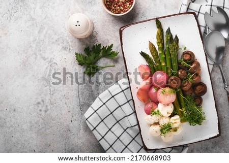 Asparagus, mushrooms, mozzarella cheese, grilled radish and cress salad, oil olive salad on rectangular ceramic plate on light gray tile table background. Healthy diet grilled food concept. Top view.