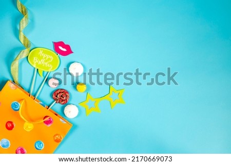 orange gift bag with sweet candies and bright party accessories