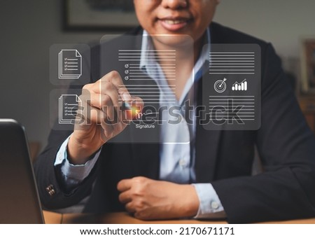 A businesswoman uses a pen to sign electronic documents on a virtual screen while sitting in the office. Electronic signature. Technology, document management, and paperless office concept