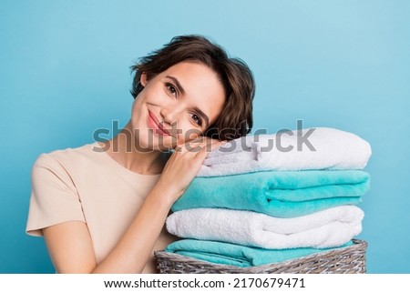 Portrait of young cute kind woman working around house leaning on pile of washed towels isolated on blue color background Royalty-Free Stock Photo #2170679471