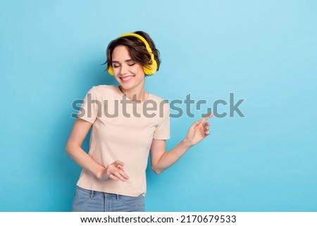 Photo of cute adorable lady dressed beige t-shirt earphones listening songs empty space isolated blue color background