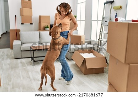 Young caucasian woman smiling confident listening to music and dancing with dog at home