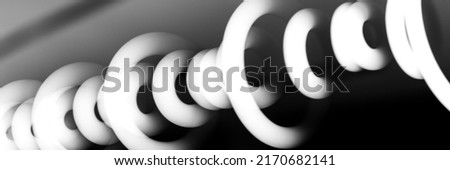 blurred hanging lamp bulb in the form of rings. blur abstract lighting modern pendant electricity round lamps chandelier glowing gray dim light inside a room. tinted in black and white. banner
