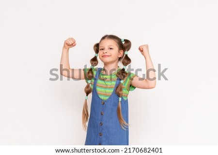 The little girl shows how strong she is. The child shows his biceps on a white isolated background.