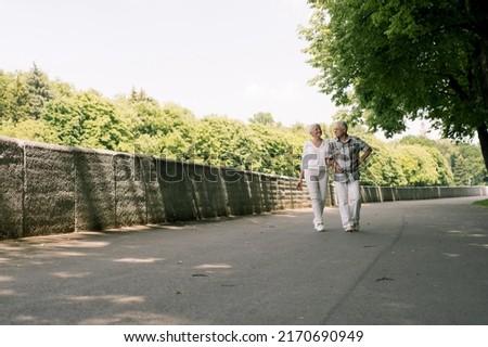 Elderly couple walking in the park on a hot summer day Royalty-Free Stock Photo #2170690949