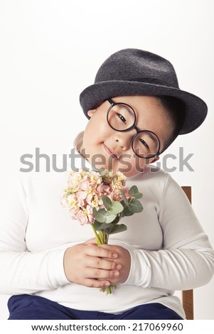 A asian boy wearing felt hat holding pink flowers for girl friends with smile.