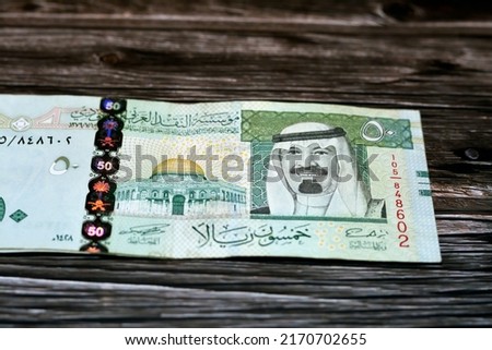 Stack of Saudi Arabia 50 SAR fifty Saudi riyals cash money banknote with the photo of king Abdullah Bin AbdulAziz Al Saud and the Dome of the Rock isolated on a wooden background, selective focus