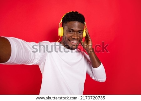 Photo of positive funky person hand touch headphones make selfie isolated on red color background