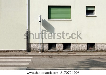 Road sign with shadow on the condominium facade. Paved sidewalk and asphalt street in front. Urban background for copy space Royalty-Free Stock Photo #2170724909