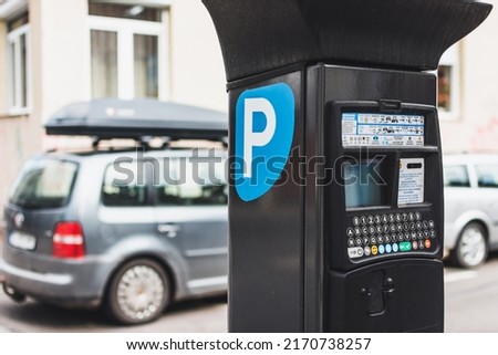 Parking meter next to a parked car. Parking ticketing in urban area concept Royalty-Free Stock Photo #2170738257