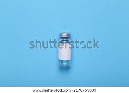 Vaccine bottle with a blank label for the brand on blue background. Top view Royalty-Free Stock Photo #2170753033