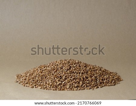 A bunch of buckwheat seeds, highlighted on a beige background, close-up. Buckwheat seeds, buckwheat grains, highlighted on a beige background, close-up. Buckwheat for porridge. 