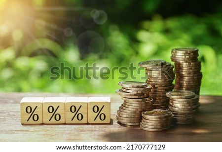 percentage icon on wood cubes, stacks of coins, nature background. increasing price concept. increase or decrease interest.             