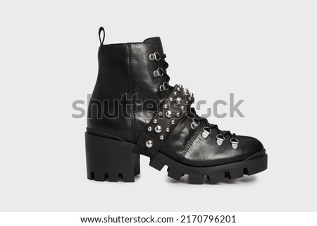 Women's fashion combat boot isolated on white background. Female classic spring autumn shoe. Leather laced casual footwear with metal rivets, spikes, buckle, high heel. Punk, emo, grunge, goth style