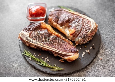 Grilled New York beef steak on the bone, herbs and spices on a stone background Royalty-Free Stock Photo #2170802461