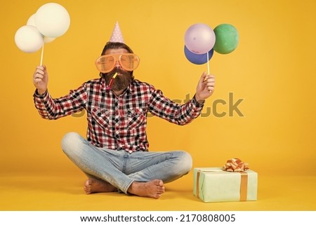 happy birthday to you. bearded mature man celebrate birthday party. cheerful man in bday hat hold holiday balloons. gifts and presents concept. have a happy holiday. party time