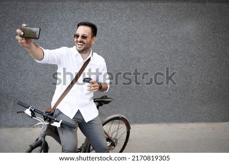 Business man taking selfie while sitting on bike