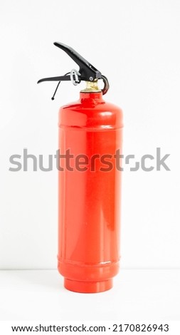 Red fire extinguisher on a white wall background.