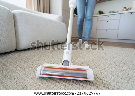 Housework and housekeeping concept. Selective focus at brush on modern and cordless vacuum cleaner. Cropped woman using professional appliance to hoovering carpet at home Royalty-Free Stock Photo #2170829767