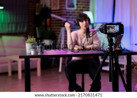 Young blogger recording online podcast discussion on camera, vlogging live channel content. Female influencer filming video conversation with audience, using streaming equipment. Royalty-Free Stock Photo #2170831471