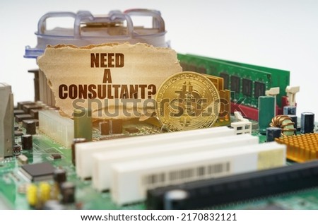 Crypto - business concept. On the motherboard lies a bitcoin coin and a cardboard sign with the inscription - Need a Consultant