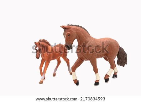 Realistic plastic toy horse and her foal. Isolate on a white background. A cute little horse figurine is a toy for children. Copy space