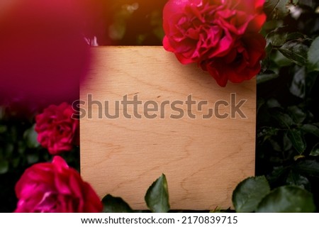 Background, inscription, signboard, cover. Wooden background with a place for an inscription in a frame of beautiful red roses.