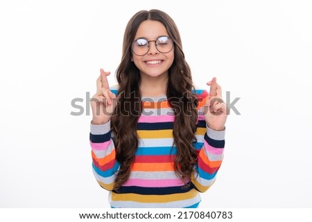 Teenager child holding fingers crossed for good luck. Portrait of cheerful girl prays and hopes dreams come true, crosses fingers for good luck, closes eyes, isolated on white studio background. Royalty-Free Stock Photo #2170840783