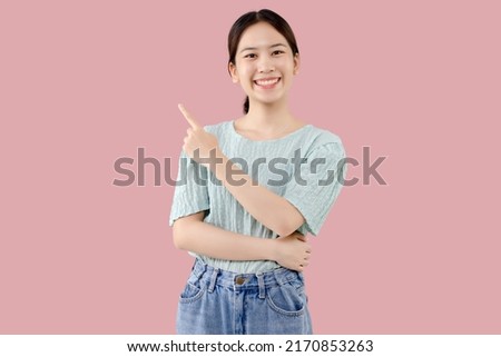 Young Asian lovely girl over isolated pink background pointing finger to the side with copy space.