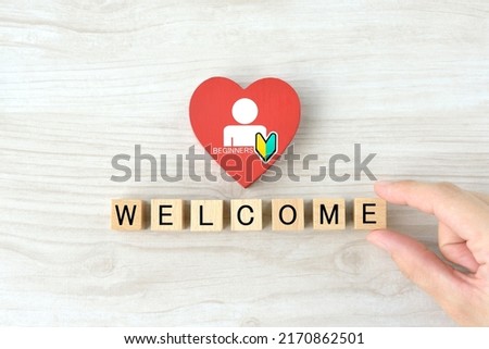 Businessman's hand with human pictogram and Japanese beginners mark drawn on heart object and wooden blocks with "WELCOME" word Royalty-Free Stock Photo #2170862501