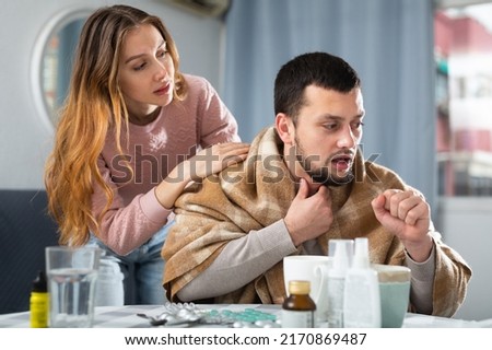Woman comforting her ill husband who sitting at table with medicines at home. Royalty-Free Stock Photo #2170869487