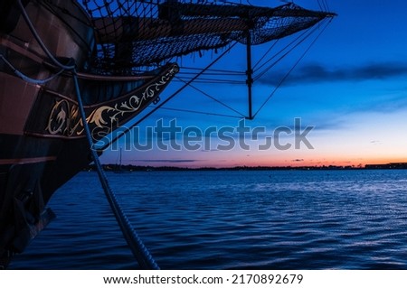 Front of wooden ship with sunset background. Ship bow with ocean sunset. Pirate ship exterior docked on boat dock. Abstract nature. Minimal industrial design. 
