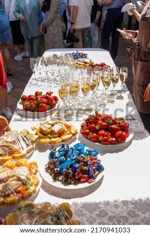 A banquet table with wine glasses and plates with snacks. Waiter fill glasses with champagne. Party concept. Selective focus.