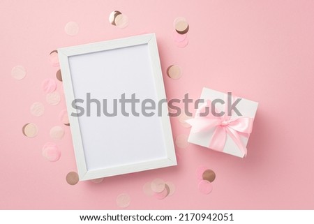 Baby girl concept. Top view photo of white giftbox with ribbon bow photo frame and shiny confetti on isolated pastel pink background with empty space