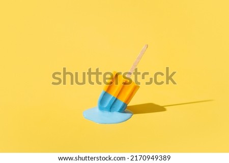 Colored yellow and blue ice cream melts from the hot sun. Hot weather concept Royalty-Free Stock Photo #2170949389