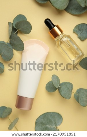 Organic skin care products on beige background with fresh green eucalyptus leaves. Vertical photo