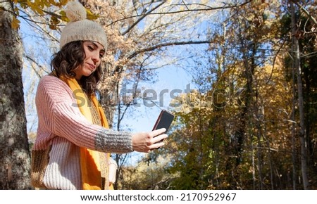 Woman taking selfies in the field. Girl using mobile phone on an excursion