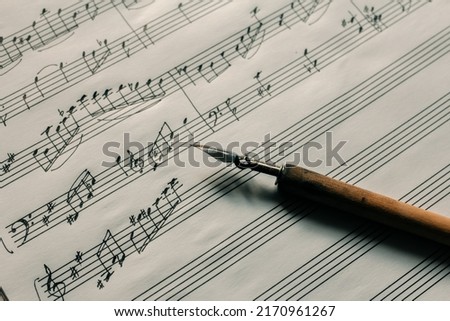 Ink pen on the background of a lined sheet with notes, writing notes, composing music Royalty-Free Stock Photo #2170961267